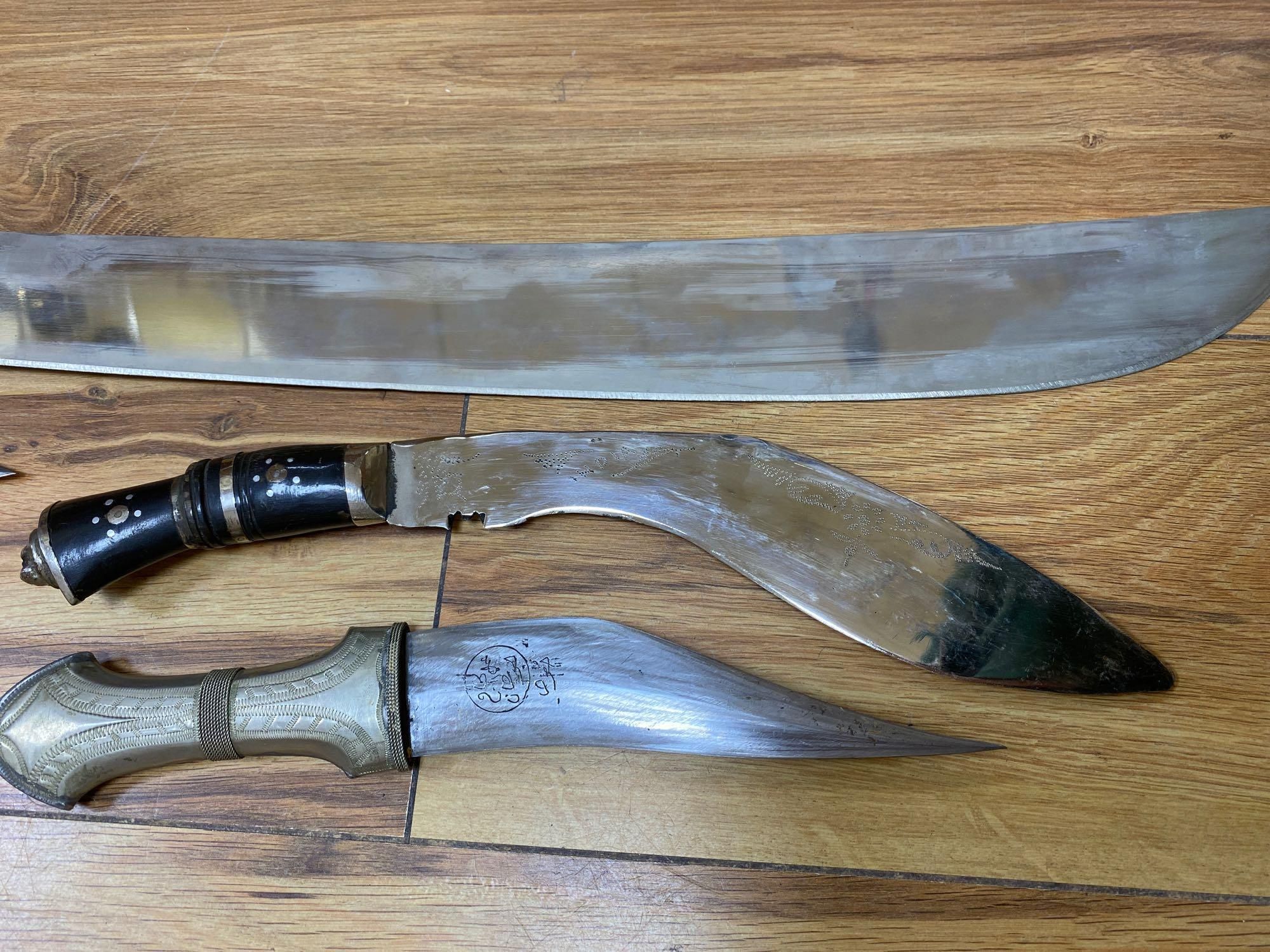 Five various weapons including a Kukri, a carved bone handled dagger with brass sun, moon and stars sheath and an El Salvador machete